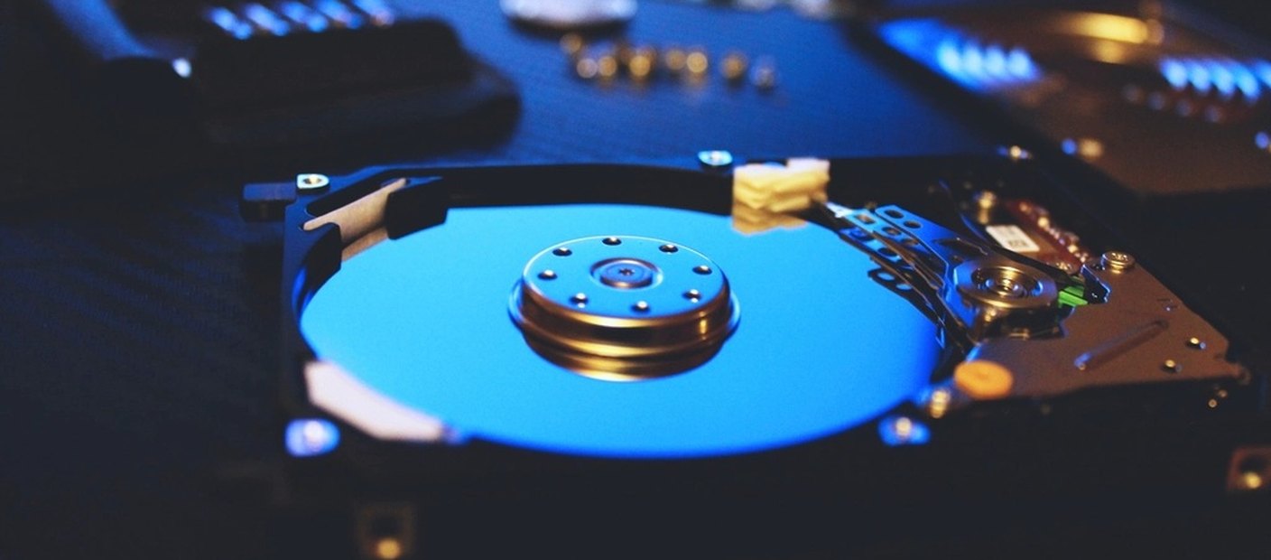 The inside of an opened computer hard drive, showing the platter and the read head arm.