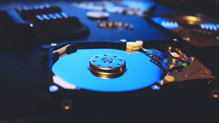 The inside of an opened computer hard drive, showing the platter and the read head arm.